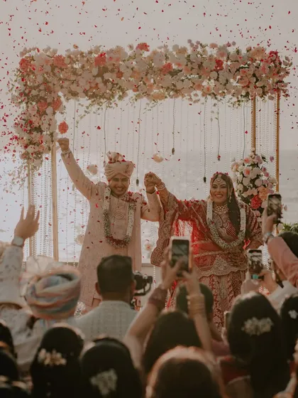 The couple celebrates their union under a shower of flowers after their beachside ceremony. This is a moment of pure triumph and happiness.