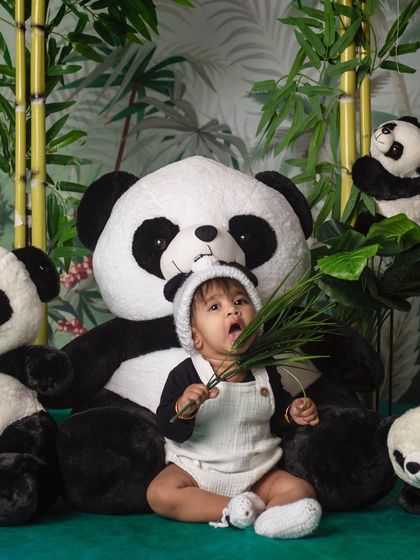 A little panda enjoying his breakfast, looking absolutely adorable and a bit surprised.