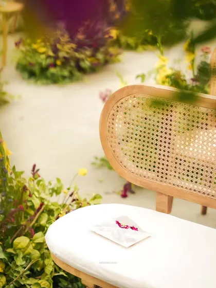 An intimate guide to a lifetime of togetherness. A personalized wedding handbook rests on a cane bench, a small, thoughtful detail for guests to enjoy during the ceremony.