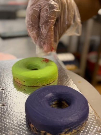 Our baker sprinkles finishing touches on our vibrant Holi dognuts. These colorful treats are a safe and delicious way to celebrate the festival of colors.