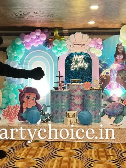 An underwater fantasy with our mermaid theme, complete with a friendly panda mascot. This stage decoration includes a pastel balloon arch, character cutouts of Ariel and a sea turtle, and themed pedestals on a raised platform.