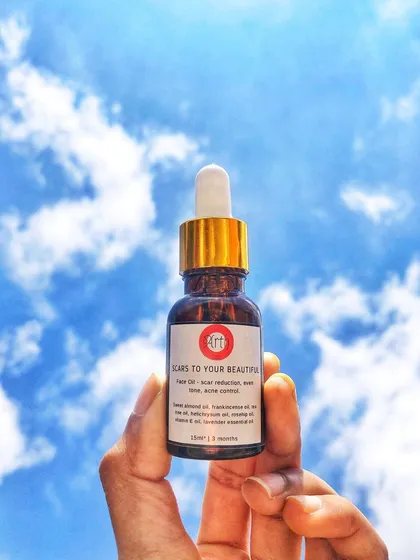 My "Scars to Your Beautiful" face oil, held up against the sky. This blend of sweet almond, frankincense, and lavender essential oils is made to help reduce scars and control acne.