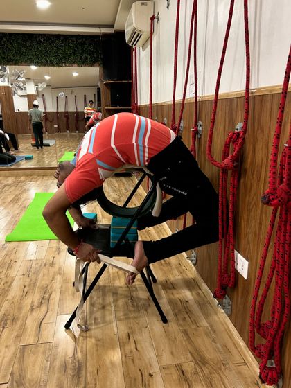Here, a yoga wheel is added to the chair setup for an even deeper backbend. The strap around the feet helps to keep the legs engaged and aligned.
