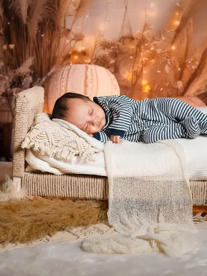 A newborn baby boy sleeping peacefully in his tiny bed. The classic striped pajamas add a touch of timeless charm to this cozy portrait.