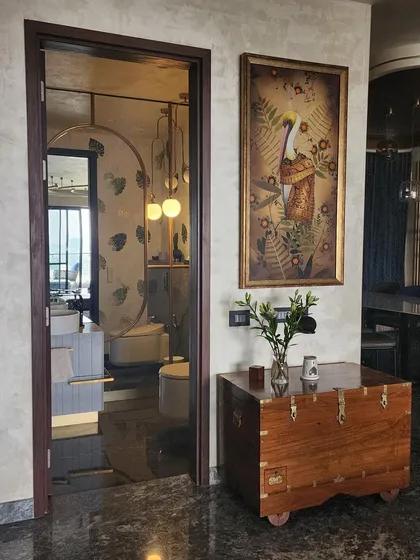 The entrance to the powder room is marked by a tinted mirror door and a beautiful piece of art. This thoughtful transition sets the stage for the carefully designed space inside, hinting at the attention to detail that awaits.