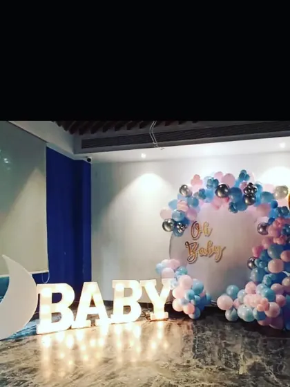 A grand "Oh Baby" shower stage with large light-up marquee letters, a crescent moon prop, and a pink and blue balloon arrangement.