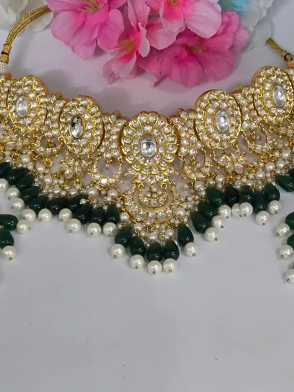 A classic Kundan choker with green beads and pearl accents. A timeless piece that complements any traditional outfit.