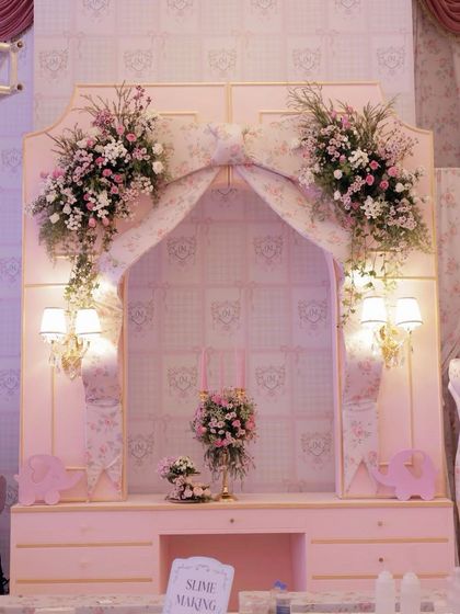 A beautiful photo backdrop with a large floral bow, elegant sconces, and custom wallpaper.