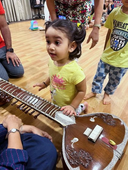 A curious toddler gets up close with a sitar. We believe that early exposure to classical instruments fosters a deeper appreciation for our rich musical heritage.