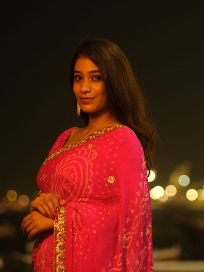 A simple and elegant portrait against the night lights of the Varanasi ghats, capturing a moment of calm during the festival.