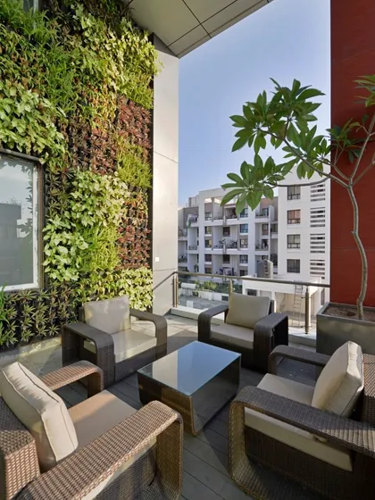 We bring nature into urban spaces with biophilic design elements. This terrace features a floor-to-ceiling vertical garden, creating a living wall of greenery that acts as a natural air purifier and a stunning visual backdrop for this outdoor lounge.