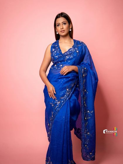 A full-length shot of a model in a beautiful blue sequined saree, showing how traditional wear can be styled for a glamorous studio look.
