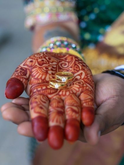 A detailed shot of the engagement rings held in the bride's henna-adorned hand, symbolizing the union of two lives.