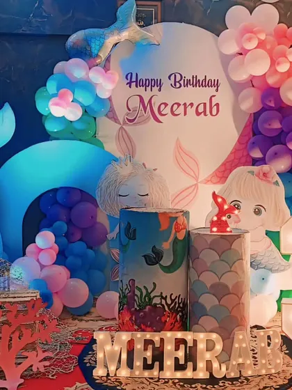 An enchanting mermaid themed birthday party, with mermaid tail props, character cutouts, and a beautiful underwater scene created with blue and pink balloons.
