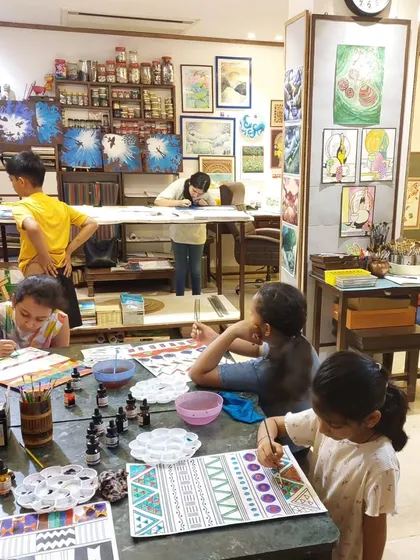 The studio is alive with color and concentration. Young artists are deeply engrossed in their pattern-making projects, using a variety of materials to explore different artistic styles.