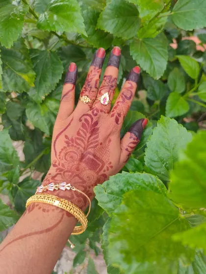 A close-up of a gorgeous, dark red henna stain against a background of green leaves. This is the color that natural, chemical-free henna can achieve.