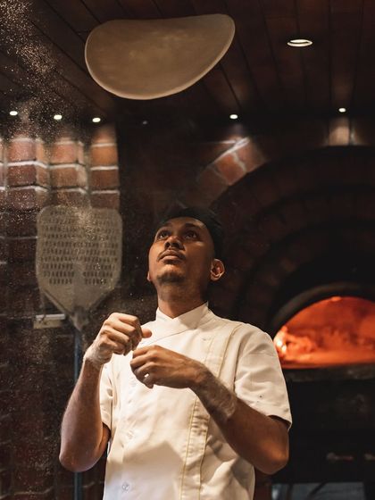 The dough seems to float above the chef's hands. Our team members are true professionals who have mastered the art of pizza making.