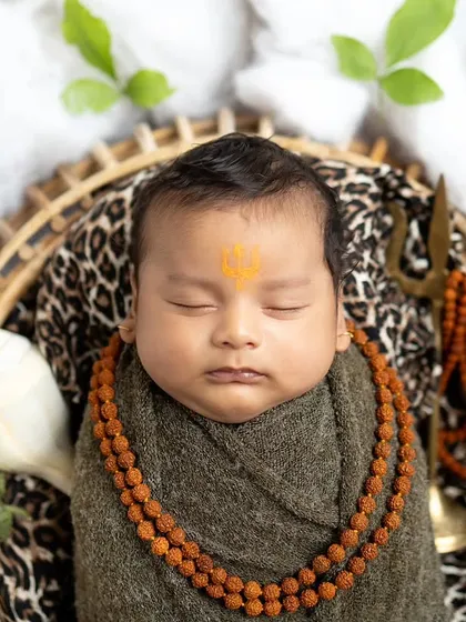 For this newborn session, we created a peaceful Mahadev theme. I focus on every little detail, from the swaddle to the props like the rudraksha and trishul, to create a divine and serene portrait.