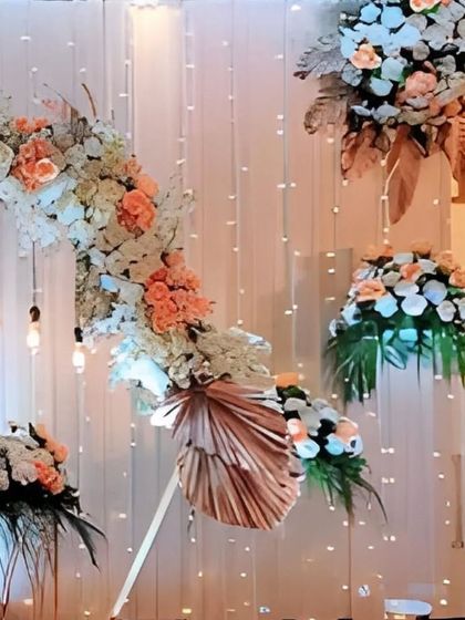 This image showcases the beautiful clusters of peach and white flowers used in the decor, accented with dried palm leaves and set against a curtain of twinkling lights.