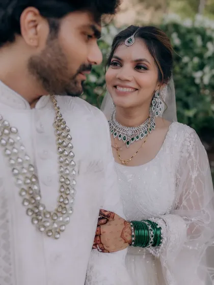 A beautiful moment between this couple. The bride wears a modern white lehenga with soft glam makeup, featuring smokey eyes and nude lips for an elegant finish.