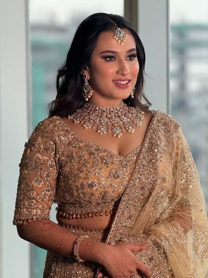 A beautiful bride in a golden lehenga, her makeup looking soft and glamorous for her reception.
