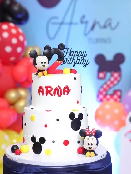 This two-tiered Mickey and Minnie Mouse cake was the star of a second birthday party. It features cute, hand-sculpted edible figures and a classic polka-dot design.