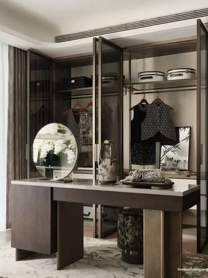 This image displays a custom walk-in closet and vanity area integrated within the master suite. The glass-paneled wardrobes and dedicated dressing table provide a functional and elegant personal grooming space.