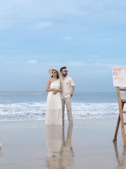A wide shot showing the couple on the beach with their creative props. This gives a sense of the beautiful, serene environment of their pre-wedding shoot.
