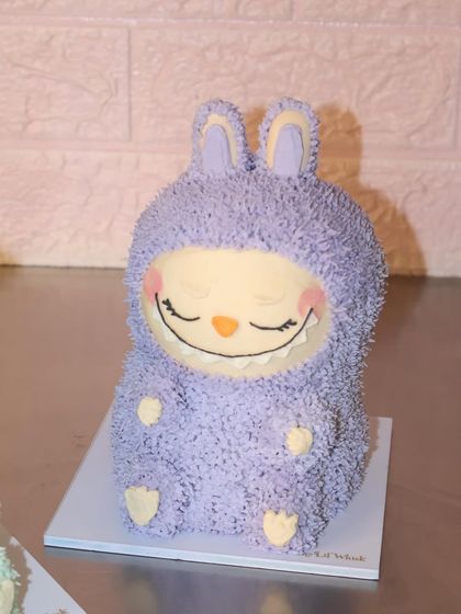 We are obsessed with this sleepy, smiling purple Labubu cake. Every detail, from the fuzzy ears to the tiny feet, is sculpted from delicious buttercream.