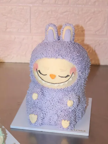 We are obsessed with this sleepy, smiling purple Labubu cake. Every detail, from the fuzzy ears to the tiny feet, is sculpted from delicious buttercream.