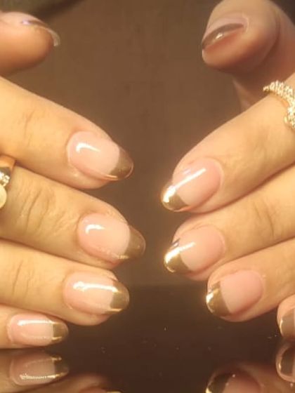 A glamorous French manicure with thick, metallic gold tips on almond-shaped nails, offering a rich and luxurious finish.