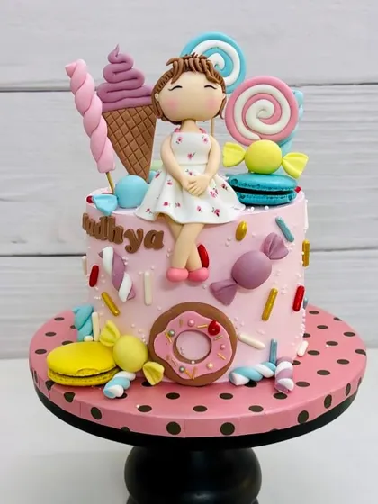 This dreamy Candyland cake was made for a little girl's birthday. It's covered in fondant candies, donuts, and ice cream cones.