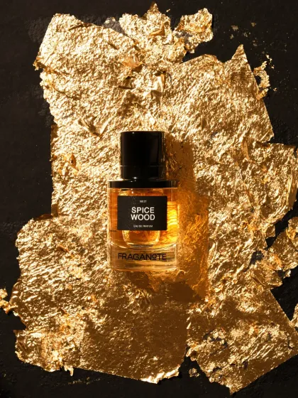 A luxury perfume shot with the bottle placed on a bed of gold leaf. This styling choice immediately communicates a sense of opulence and high value.