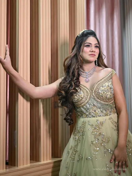 A model posing in a pastel green embroidered gown. The intricate beadwork on the bodice and the flowing tulle skirt create a look of timeless elegance.