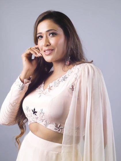 A portrait of the model in our pastel godet lehenga, showing off the unique one-sided sleeve and the delicate embroidery on the blouse.