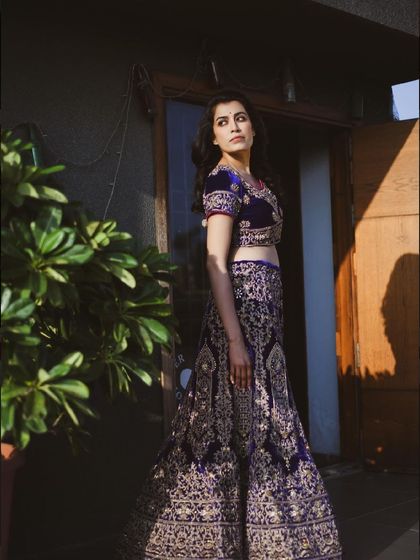 A full-length shot of a woman in a stunning lehenga, taken outdoors. The natural light highlights the intricate details of the embroidery.
