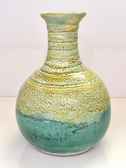 This "Coral Coast" vase is inspired by the colors of the sea. The textured glaze transitions from a sandy yellow to a sea green, creating a beautiful ombre effect.