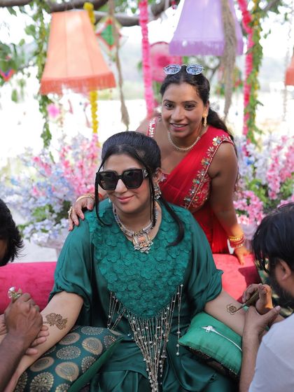 The bride gets her mehendi done, surrounded by friends and vibrant, festive decor.