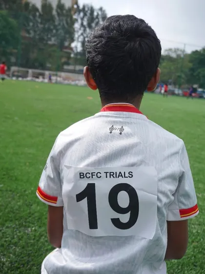 A young trialist watches the game, ready for his chance to impress. Every player is assigned a number for easy identification by our scouts.