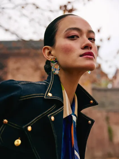 A beauty shot from the Ani Clothing campaign. The model's natural makeup and elegant pose are highlighted by the soft, diffused light of the outdoor setting.
