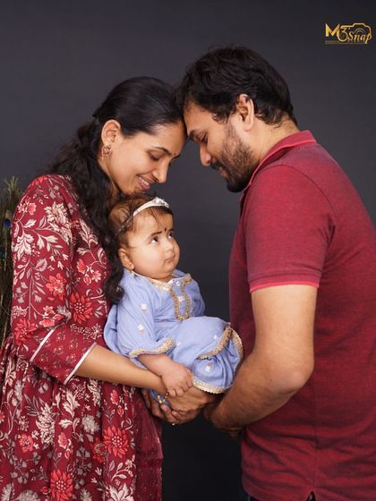 A classic family pose, with the parents' heads touching as they lovingly hold their baby. This composition emphasizes their unity and the new life they've created together.