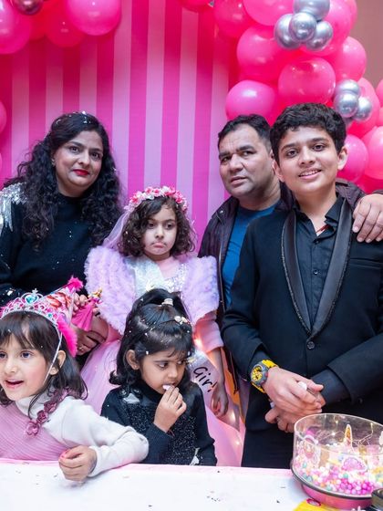 A family photo from the Barbie-themed party, capturing a sweet moment around the cake.