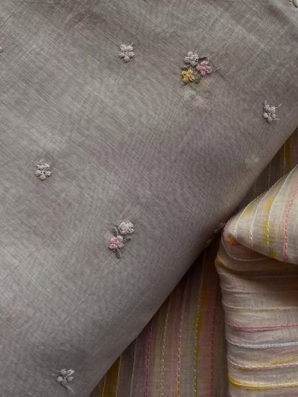 A set of grey Mul Chanderi fabrics, one with delicate floral embroidery and the other with a complementary striped pattern. Perfect for mix-and-match outfits.