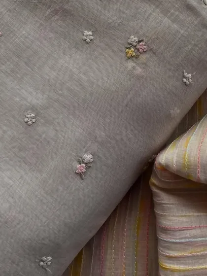 A set of grey Mul Chanderi fabrics, one with delicate floral embroidery and the other with a complementary striped pattern. Perfect for mix-and-match outfits.