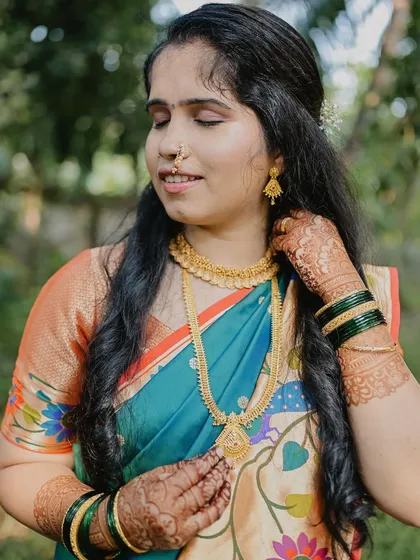 A beautiful bride adorned with gold jewelry and a stunning mehendi stain. The rich color of the henna complements her traditional attire perfectly.