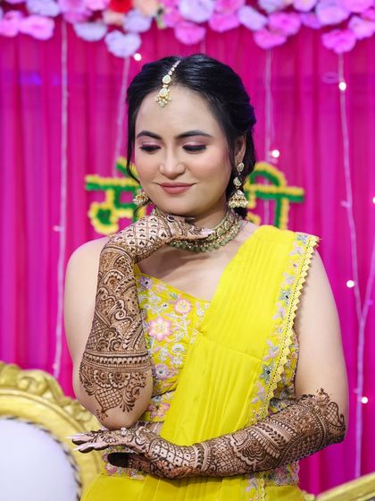 A serene pose, admiring her beautiful mehndi. The soft pink eyeshadow complements the yellow of her outfit.