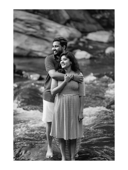 This black and white photo captures a candid moment of joy and affection, highlighting the couple's natural interaction.