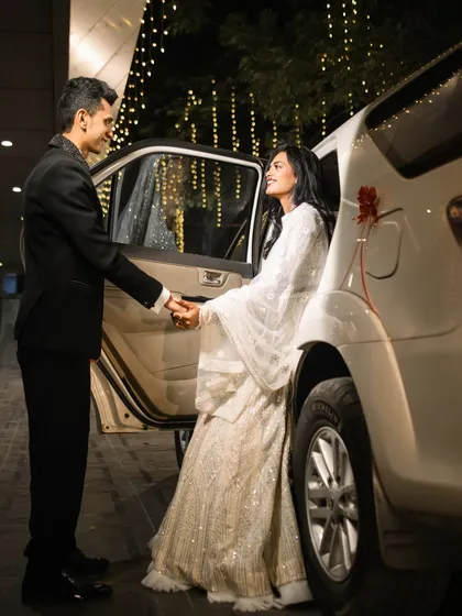 A chivalrous moment as the groom helps his bride out of the car. This candid yet perfectly composed shot tells a story of care and elegance, set against the backdrop of nighttime city lights.