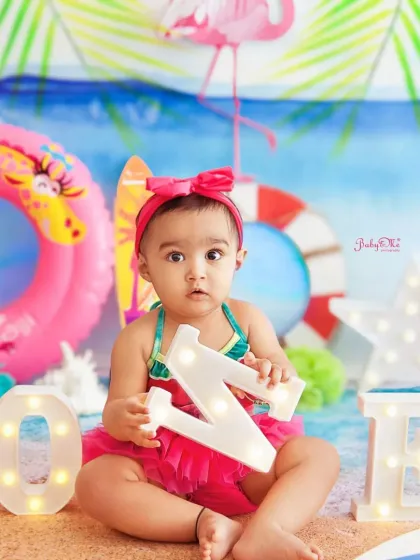 This little beach baby is all set for a day of fun in the sun with her flamingo floatie and 'ONE' letters.