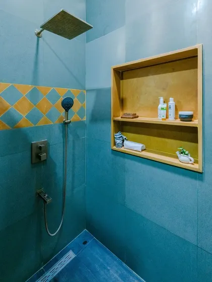 The combination of the blue stone, patterned tiles, and the warm wood of the shower niche creates a balanced and inviting bathroom design.